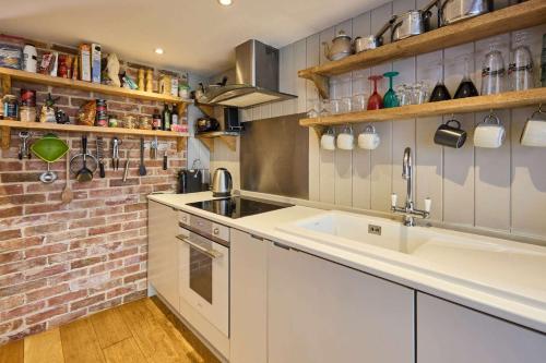 - une cuisine avec un évier et un mur en briques dans l'établissement Host & Stay - Romney Cottage, à Corpusty
