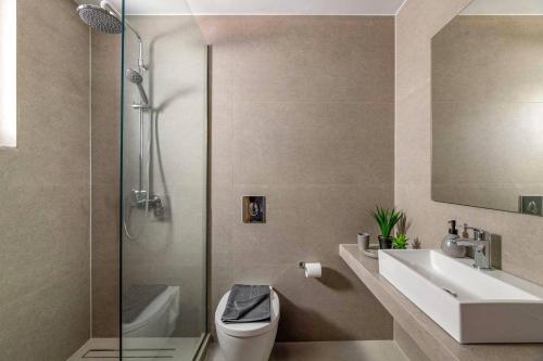 a bathroom with a toilet and a sink and a shower at Villa Palm Vista by Villa Plus in Kremasti