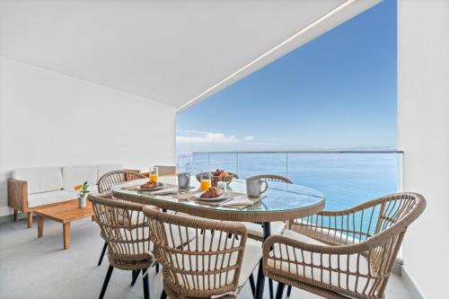 a dining room with a table and chairs and the ocean at Atlantis Apartment in Câmara de Lobos