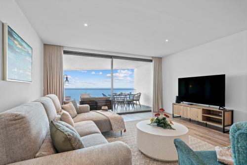 a living room with a couch and a tv at Atlantis Apartment in Câmara de Lobos