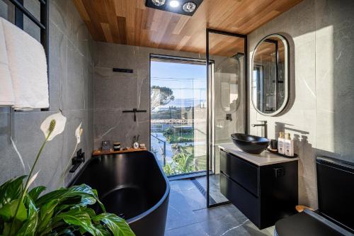 a bathroom with a black tub and a sink at Ocean breeze homestays 1 in Bicheno
