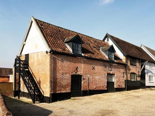 a large brick building with a staircase in front of it at Carleys Yard by The Suffolk Cottage Collection in Framlingham
