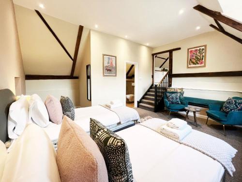 une grande chambre avec deux lits et un escalier dans l'établissement Carleys Yard by The Suffolk Cottage Collection, à Framlingham
