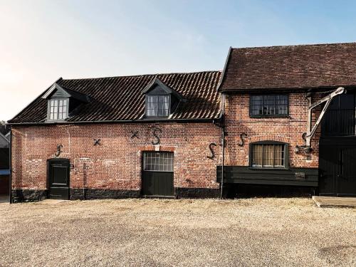 a red brick building with two doors and two windows at Carleys Yard by The Suffolk Cottage Collection in Framlingham