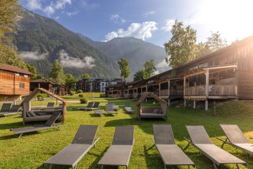 a resort with lounge chairs and mountains in the background at Lake Resort Pressegger See in Hermagor