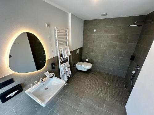 a bathroom with a sink and a toilet and a mirror at Central Hotel in Flensburg