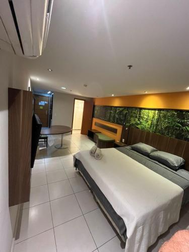 a bedroom with a large bed and a table at Flat Studio Conforto do 9 Andar in Nova Iguaçu