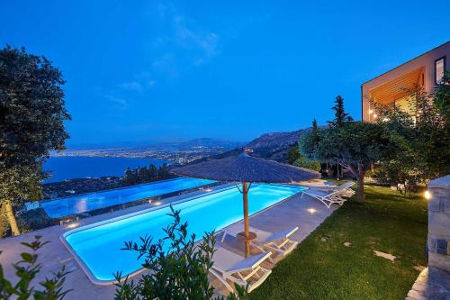an outdoor swimming pool with an umbrella and chairs at Villa Vollard Panoramic Seaview & Private Pool in Rodia