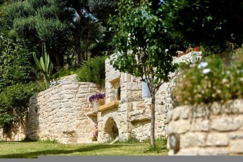 a stone wall with a tree in the grass at Villa Vollard Panoramic Seaview & Private Pool in Rodia