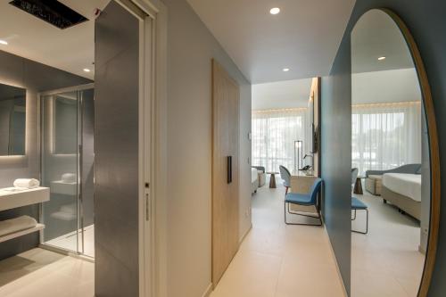 a bathroom with a mirror and a room with a bed at Ambasciatori Suite Hotel in Sottomarina