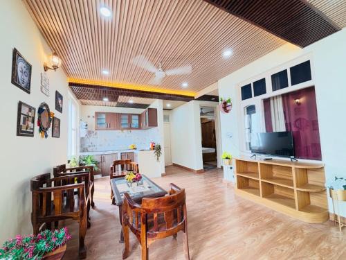 カソーリにあるPinewood Sunrise Homestay Kasauliのテーブルと椅子とテレビのあるリビングルーム