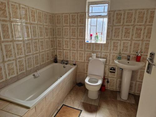 a bathroom with a tub and a toilet and a sink at Cosy Harare Haven Cottage in Harare