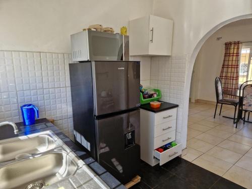 a kitchen with a black refrigerator and a sink at Cosy Harare Haven Cottage in Harare
