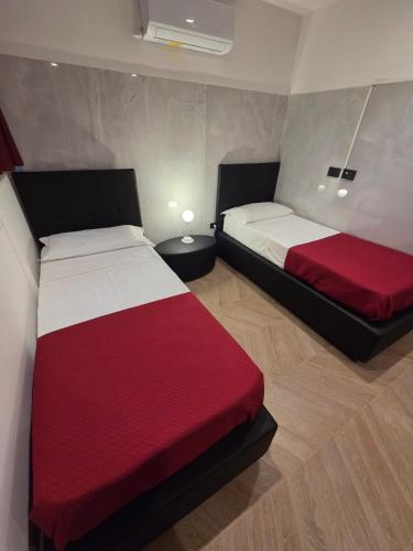a bedroom with two beds with red and white sheets at Hotel XBusiness in Nola