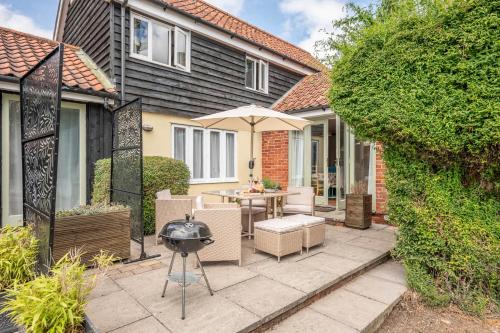 a patio with a grill and a table and chairs at The Hayloft Boundary Farm, Framlingham in Woodbridge