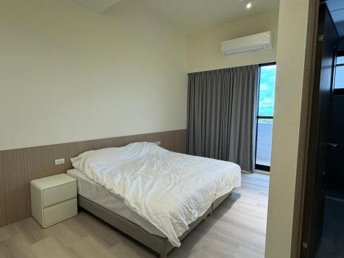 a bedroom with a white bed and a window at Miruku in Taitung City