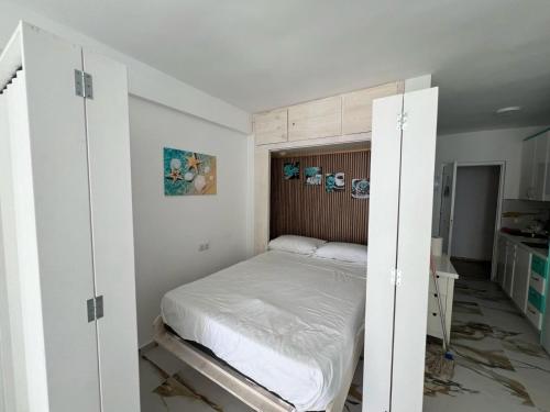 um pequeno quarto com uma cama e armários brancos em ARIES Edificio em Benidorm