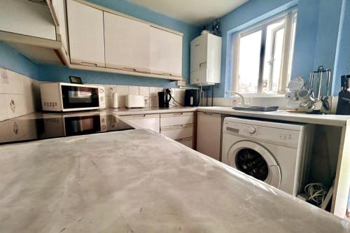 a kitchen with a washing machine in the middle at Oldham Bungalow Retreat: 2BD Peaceful Comfort in Lees