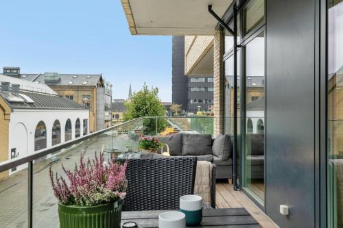 a balcony with a couch and a view of a city at Heart of Aarhus, modern apartment and paid parking nearby in Aarhus