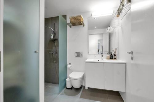 a white bathroom with a toilet and a sink at Heart of Aarhus, modern apartment and paid parking nearby in Aarhus