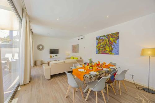 a dining room and living room with a table and chairs at Villa Jade II in Can Picafort