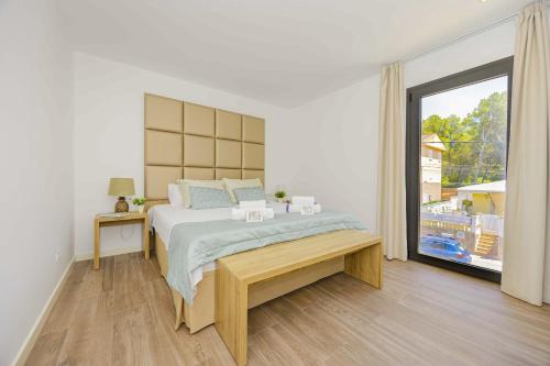 a white bedroom with a bed and a large window at Villa Jade II in Can Picafort
