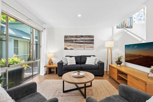 a living room with a couch and a tv at Beach Haven at Aanuka Beach Resort Diggers Beach in Coffs Harbour