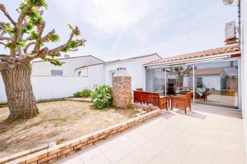 une terrasse avec un arbre, une table et des chaises dans l'établissement Nice family house - Le Bois-Plage en Ré, au Bois-Plage-en-Ré