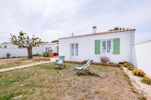 deux chaises dans la cour d'une maison blanche dans l'établissement Nice family house - Le Bois-Plage en Ré, au Bois-Plage-en-Ré