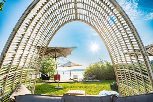 an archway over a lawn with chairs and an umbrella at Strandhotel Schmerikon in Schmerikon