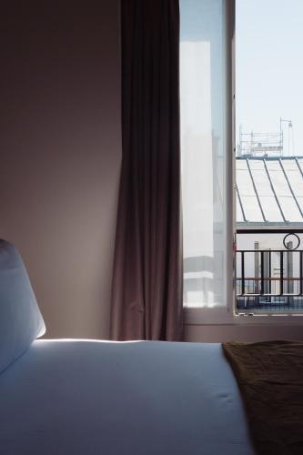 a bedroom with a bed and a large window at LALA Hôtel in Paris