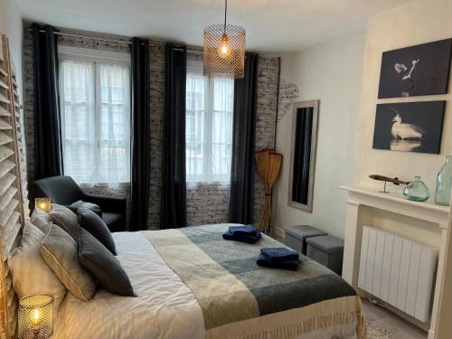 a bedroom with a bed and a chair and windows at Ptit Somme en Baie in Saint-Valéry-sur-Somme