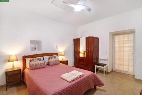 a bedroom with a large bed with a pink blanket at A Casa dos Avós in Pêra