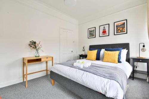 a bedroom with a bed with yellow and blue pillows at Stunning Cardiff Bay House in Cardiff