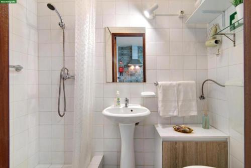 a white bathroom with a sink and a shower at A Casa dos Avós in Pêra