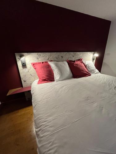 a bed with two red pillows on top of it at La Roselière du Der in Giffaumont