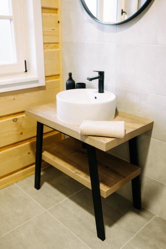 a bathroom sink on a wooden table with a mirror at Chalupa na Políčku in Hanička