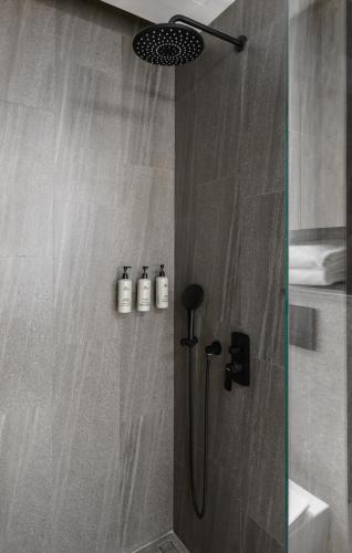 a shower with a glass door with three bottles at Amazing La Green 10 min walk to Layan Beach in Layan Beach