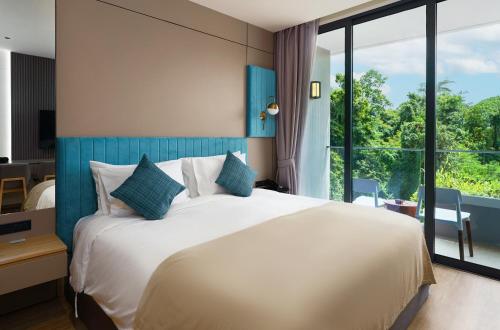 a bedroom with a large bed and a large window at Amazing La Green 10 min walk to Layan Beach in Layan Beach