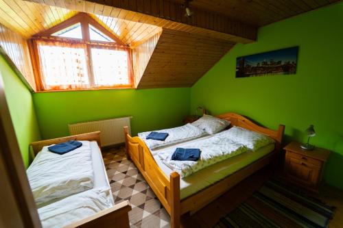 a green bedroom with two beds and a window at Penzion HACIENDA in Liptovská Osada