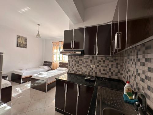 a kitchen with black cabinets and a couch in the background at Esmeralda Hotel & Restaurant in Ksamil