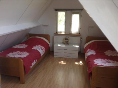 a attic bedroom with two beds and a window at Huisje Meerweg in Rohel