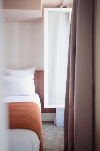 a bedroom with a bed and a window at LALA Hôtel in Paris