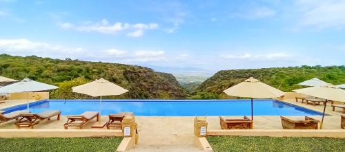 a swimming pool with chairs and umbrellas at Africa Safari Manyara Escarpment in Mto wa Mbu