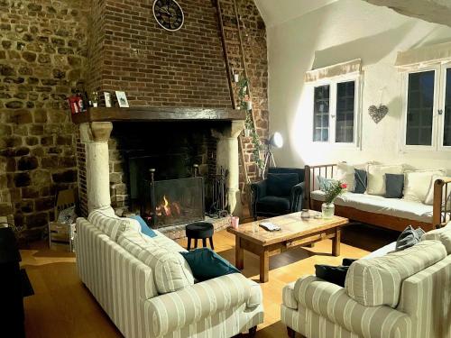 un salon avec deux canapés et une cheminée dans l'établissement Grande chaumière, 5 chambres, 14 personnes proche des plages, à Manneville-ès-Plains