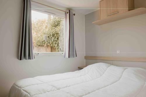 une chambre avec un lit blanc et une fenêtre dans l'établissement Camping VAL FLEURI ATC Cagnes-Sur-Mer, à Cagnes-sur-Mer
