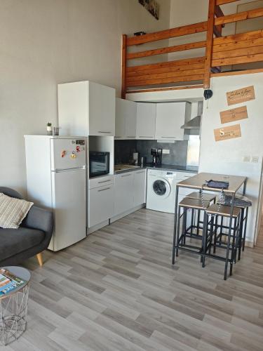 - une cuisine avec des appareils blancs, une table et des chaises dans l'établissement L'anse duRhône, à Port-Saint-Louis-du-Rhône