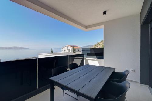a table and chairs on a balcony with a view of the water at Apartmani Olimp2 in Sveti Juraj