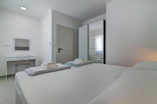 a white bedroom with a large white bed and a bathroom at Apartmani Olimp2 in Sveti Juraj