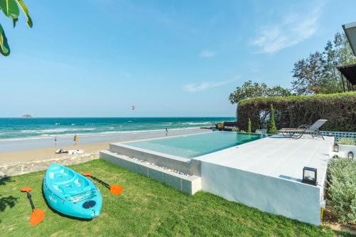 a blue kayak sitting on the grass next to a beach at 26Villa Huahin in Khao Tao